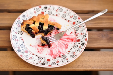 Remains of homemade lattice blueberry pie in square white plate with fork closeup macroの写真素材