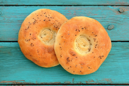 Two round chapatis with sesam seeds on blue wooden table closeup top viewの写真素材