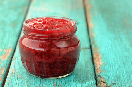Nice glass jar with homemade sweet raspberry jam on old turquoise table  copyspace