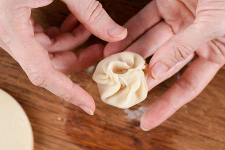 Cooking techniques. Closeup of woman hands making purse shape dumpling momo closeup macroの写真素材