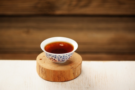 Black puerh tea in white bowl on wooden stand copyspace selective focusの写真素材