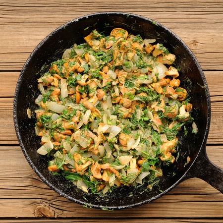 Fried chanterelle mushrooms with greens in black cast iron pan squareの写真素材