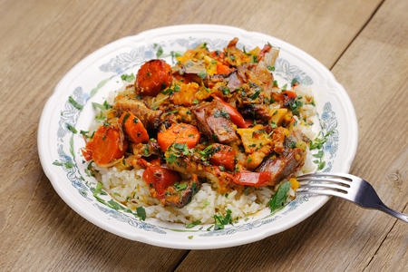 Lamb ragout with vegetables and rice in white plate on wooden backgroundの写真素材