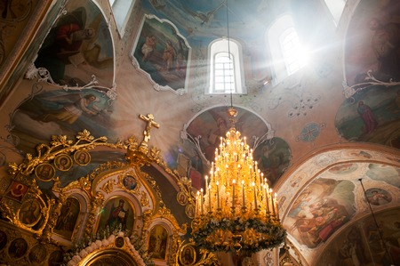 Orel, Russia - July 28, 2016: Russian Orthodox church interior. Sun rays through windows, huge chandelier with candles and iconsのeditorial素材