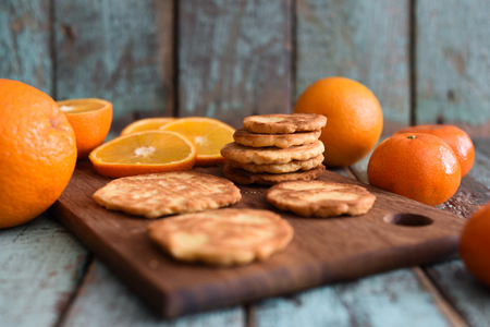 Vegetarian healthy sweets. Homemade tasty cookies with raw oranges and clementines on shabby blue wooden background closeupの写真素材