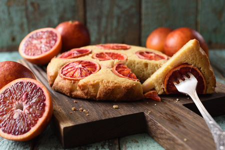 Homemade imperfect cake with blood oranges on oak board closeupの写真素材
