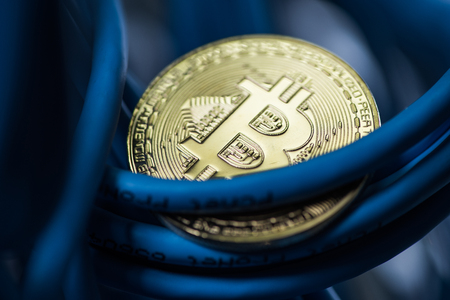 Shining bitcoin coin in blue cables closeup. Cryptocurrency, digital curency mining concept closeupの写真素材