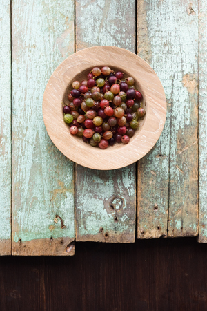 Organic berries. Healthy snack. Raw gooseberries in oak plate on rustic wooden background copyspace top viewの写真素材