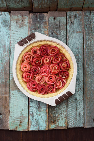 Homemade healthy dessert. Raw apple rose pie in baking dish on old blue table above view copyspaceの写真素材