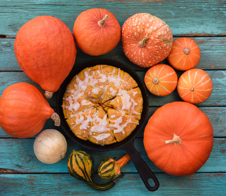 Homemade dessert. Traditional pumpkin scones with sugar icing cut into triangular sections in cast iron pan  on blue background copyspace top viewの写真素材