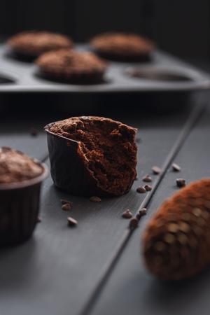 Hygge cozy dessert. Half eaten tasty chocolate muffins with small chocolate chips on dark background verticalの写真素材