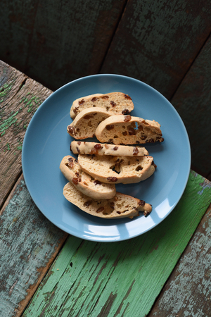 Homemade Italian biscuits biscotti with raisins in blue plate on old shabby wooden background top view copyspaceの写真素材