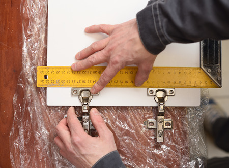 Carpenter at work. Measuring door hinges on wooden door with ruler overhead view