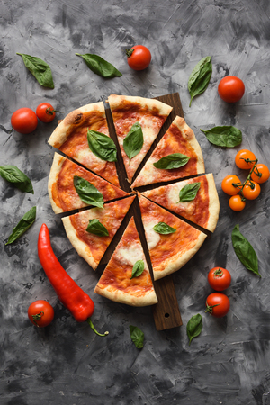 Italian rustic pizza Margherita with raw tomatoes, basil and bell pepper on dark background top view copyspaceの写真素材