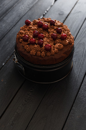 Yummy homemade chocolate cake with chocolate icing and cherries on dark background minimalist style copyspaceの写真素材