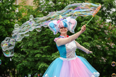 Orel, Russia, May 26, 2019: Twin Festival. Smiling woman in bright unicorn costume making big soap bubbles selective focusのeditorial素材