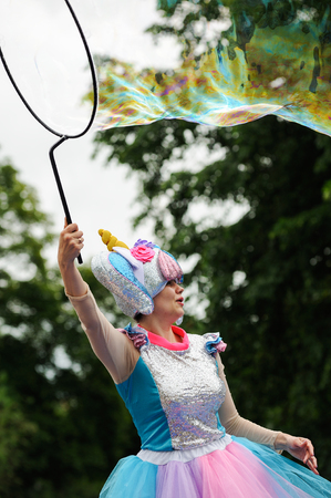 Orel, Russia, May 26, 2019: Twin Festival. Happy woman in bright fancy costume making big soap bubbles verticalのeditorial素材