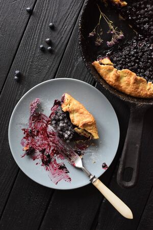 Healthy homemade pastry. Delicious crusty blueberry galette being eaten on black background top viewの写真素材