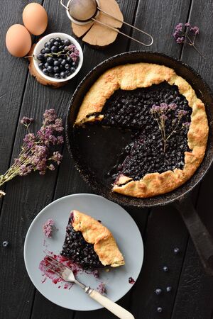 Homemade blueberry pie in cast iron pan with ingredients on black background top viewの写真素材