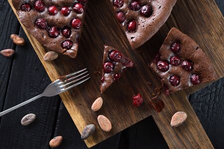 Homemade comfort food. Flatlay of yummy chocolate brownies with tart cherries and cocoa beans on dark background overhead viewの写真素材