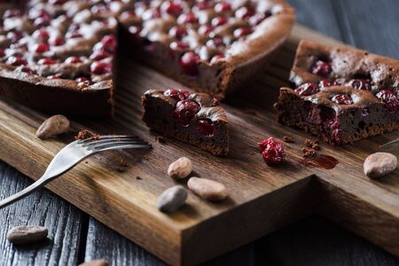 Yummy chocolate dessert. Homemade brownies with cherries and cocoa beans on oak board low angle viewの写真素材