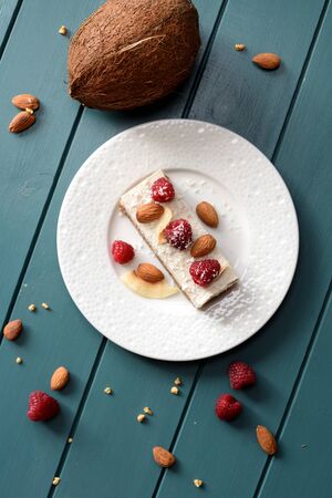 Healthy sugar free vegan dessert. Coconut milk cheesecake with raspberries and almonds and whole coconut on dark background top view copy spaceの写真素材