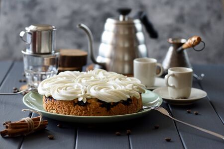 Homemade cake with white rose shaped icing served with coffee on dark grey  background copy space....