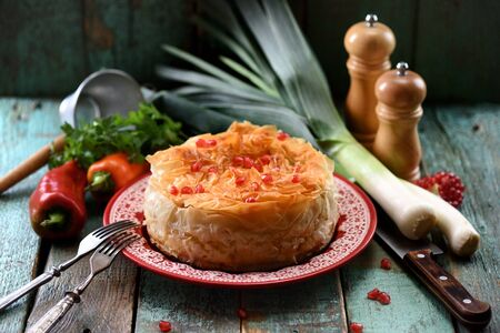 Homemade oriental style phyllo pie with vegetables decorated with pomegranate seeds on old blue boards close upの写真素材