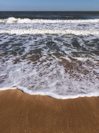 Vacation concept. Minimalist seascape of Crimea with foamy waves on sandy beach and clear blue sky...