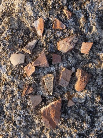 Fragments of ancient ceramic pottery on sea shore top view texture background overhead view