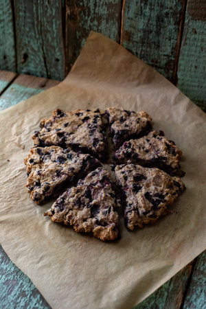 Blueberry rustic scones on bake paper  and oak cutboard on old painted wood background with copyspaceの写真素材
