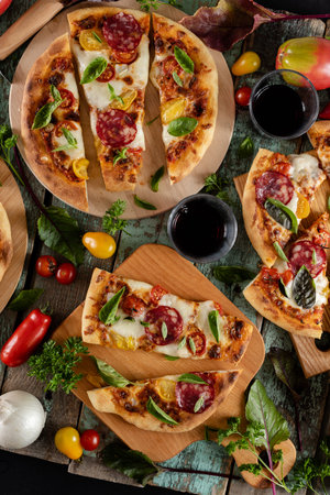 Pizza with mozzarella, salami and basil on wooden backgroundの写真素材