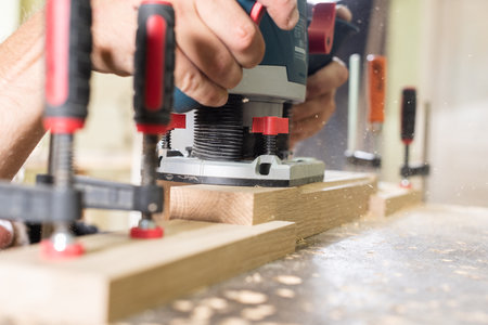 A carpenter is milling an oak plank with a manual milling machine closeup
