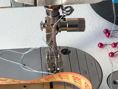 table with a sewing machine, sewing accessories are on the table, needles, scissors, rulers. threads
