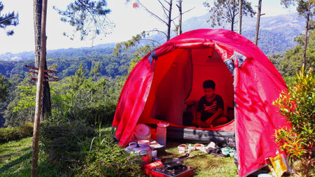 Surabaya, Java, Indonesia - July, 2022 : boy camping at mountain with his family during school holidayのeditorial素材