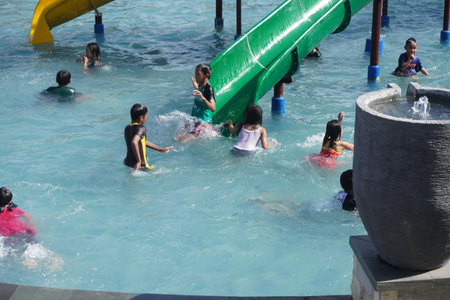 Surabaya, East Java, Indonesia - July, 2022 : Happy and joy kids playing with kids pool slide at the swimming poolのeditorial素材
