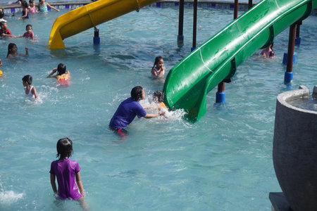 Surabaya, East Java, Indonesia - July, 2022 : Happy and joy kids playing with kids pool slide at the swimming poolのeditorial素材