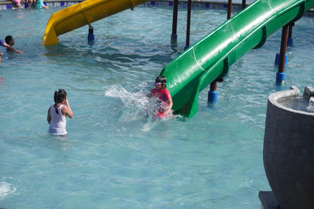 Surabaya, East Java, Indonesia - July, 2022 : Happy and joy kids playing with kids pool slide at the swimming poolのeditorial素材