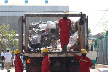 Surabaya, Indonesia - June 2022 : The cleaners are collecting garbage into the garbage truck to take it to the garbage dumpのeditorial素材