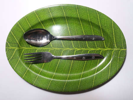 Green plate leaf theme isolated white background with spoon and forkの写真素材