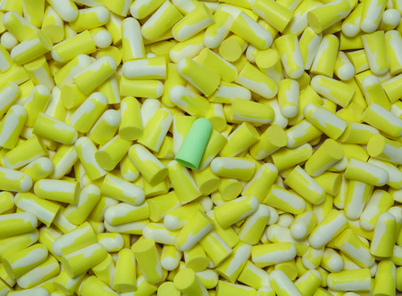 Green ear plug on the several yellow ear plug background.の写真素材
