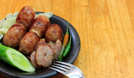 Thai style sausage and vegetable cabbage, cucumbers, chili,fork in the dish on wood background.の写真素材