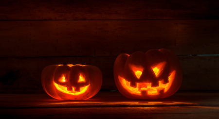 Bright light in pumpkins on wood background by dark light tone.の写真素材