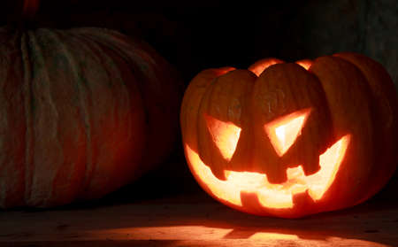 Selective focus bright light in pumpkins on wood and pumpkins background by dark light tone.の写真素材