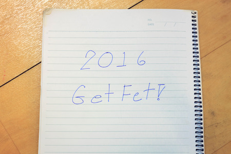 Text 2016 get fit on notebook, wood background.