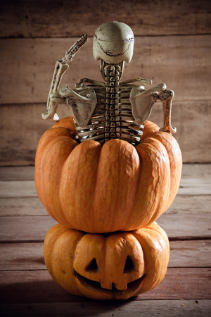 Skeleton is saluting on pumpkin and blur background.の写真素材