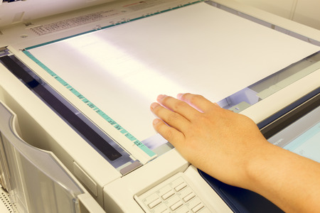 someone copy document at copy machine.non-English text mean "CAUTION Do not stare at light.It may cause discomfort or irritation to your eyes,"の写真素材