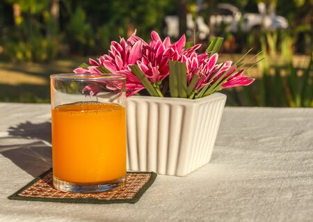 orange juice on saucer.saucer and flower in vase on the cloth in the morning.の写真素材