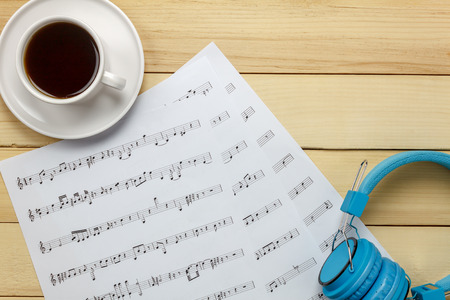 Create music sheet note paper by myself.Top view music sheet note paper,headphones,coffee on wood background.の写真素材