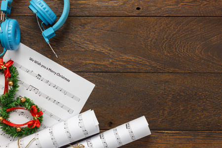 Top view Christmas music note paper  with Christmas decoration and headphones on wooden table background.Create this music note paper myself.の写真素材